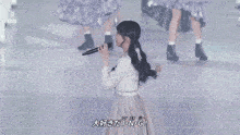 a girl is singing into a microphone with chinese writing on the bottom