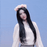 a woman with long black hair wearing a white sweater and a flower crown on her head