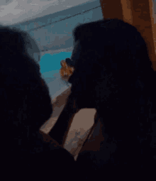 a man and a woman are kissing in front of a swimming pool