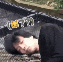 a man laying on the ground with a cat on his head and a question mark behind him