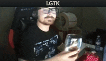 a man with glasses is holding a glass in front of a lgtk banner
