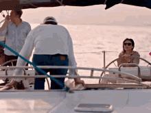 a woman sits at the helm of a boat while a man stands behind her