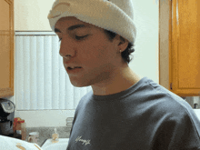 a young man wearing a beanie and a gray shirt that says young on it