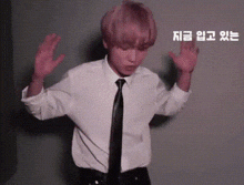 a man in a white shirt and black tie is dancing with his hands in the air .