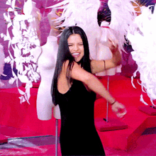 a woman in a black dress is dancing in front of a display of mannequins