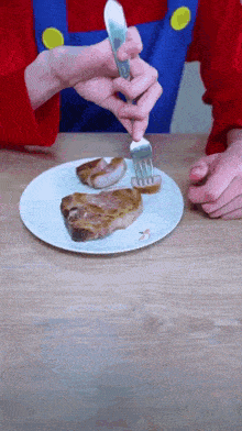 a person holding a fork over a plate of meat