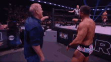a wrestler is pointing at another wrestler in a wrestling ring .