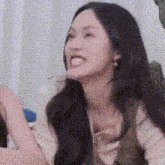 a woman with long black hair is making a funny face while sitting on a couch .