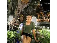 a woman in a green top and black shorts is sitting on a wooden bench