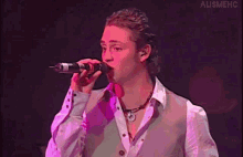 a man singing into a microphone with the word alismehc on the bottom right corner