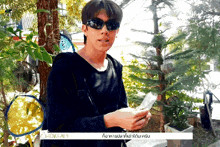 a man wearing sunglasses holds a piece of paper in front of a sign that reads chokun