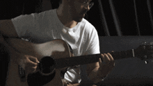 a man wearing glasses is playing a guitar