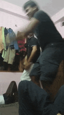 a man in a black shirt is standing on another man 's lap