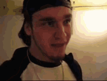 a close up of a man wearing a hat and a white shirt .