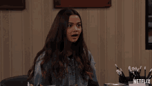 a girl sitting at a desk with a netflix logo in the corner