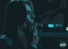 a woman is smoking a cigarette in a dark room with a lot of smoke coming out of her mouth .