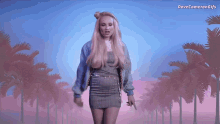a woman in a dress is dancing in front of palm trees and the words dove cameron gifs are above her