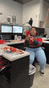 a woman in a red sweater sits at a desk with a sign that says caution