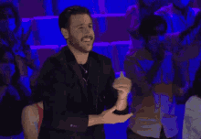 a man with a beard is dancing in front of a crowd of people