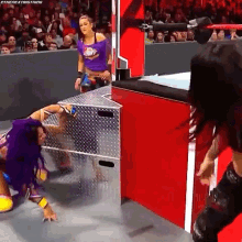 a woman in a purple shirt is wrestling another woman in a purple shirt in front of a crowd .