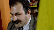 a man with a mustache and a suit and tie is looking at something