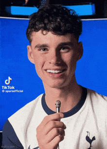 a young man in a spurs shirt holds a small microphone
