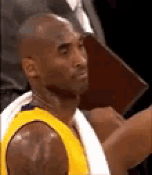 a basketball player in a yellow jersey is sitting on the bench .