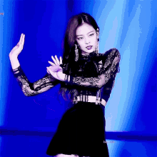 a woman in a black dress is dancing on a stage with her hands in the air .
