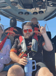 a man sitting on a boat wearing a life jacket that says west marine on it