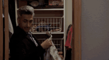 a man standing in a closet looking at clothes