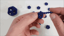 a person is holding a string of blue beads between their fingers