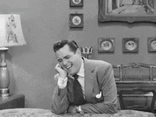a man in a suit and tie is sitting at a table talking on a phone .