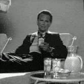 a man sits in a chair holding a bottle that says atomic