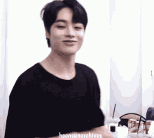 a young man wearing a black shirt with the words hoonsunarchives written on the bottom