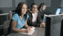 a group of people are sitting at a desk in front of a computer monitor .