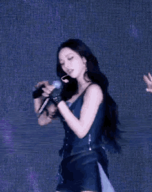 a woman in a blue dress is singing into a microphone on stage .