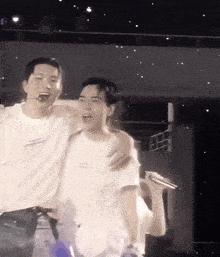 two men are hugging each other on a stage and one of them has a t-shirt that says ' i love you '