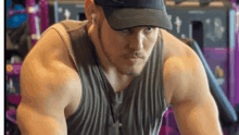 a man wearing a hat and a tank top is looking down
