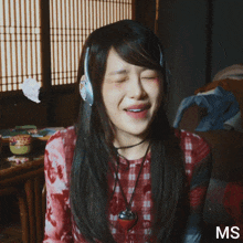 a woman wearing headphones and a plaid shirt with the letters ms on the bottom right