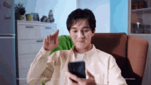 a man is sitting in a chair looking at a cell phone