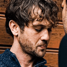 a man with curly hair and a beard is looking down