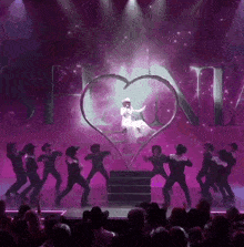 a woman in a cowboy hat is sitting in a heart surrounded by cowboys on a stage