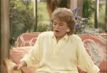 a woman in a yellow shirt is sitting on a pink couch .