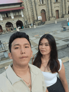 a man and woman pose for a picture in front of a building