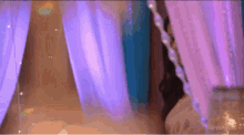 a woman is standing in a room with purple curtains and candles .