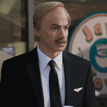 a man in a suit and tie stands in front of a coffee shop