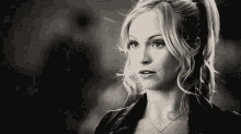 a black and white photo of a woman with blonde hair in a ponytail and a necklace .