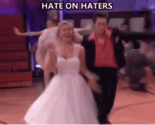 a woman in a wedding dress is dancing on a dance floor with a man in a red jacket .