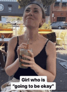 a woman in a black tank top drinking a green drink with a straw