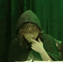 a woman wearing glasses and a cape with a hood is sitting at a table .